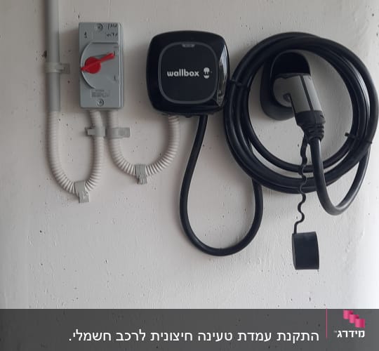 מטען חשמלי לרכב עם כבל תלוי על הקיר